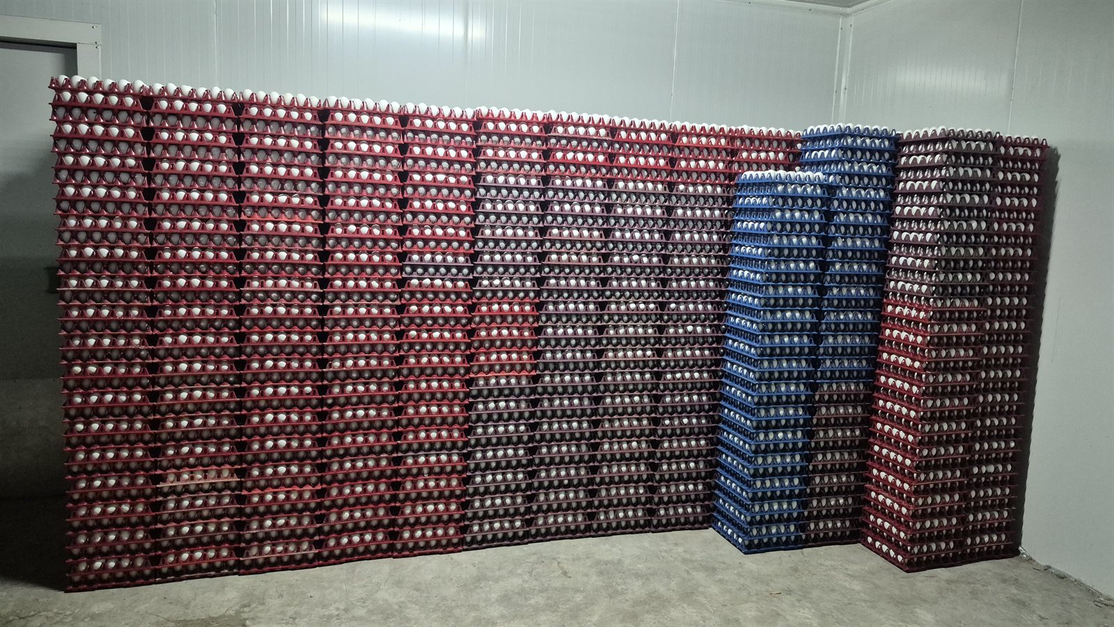 Large wall of packed egg crates stacked inside the storage room