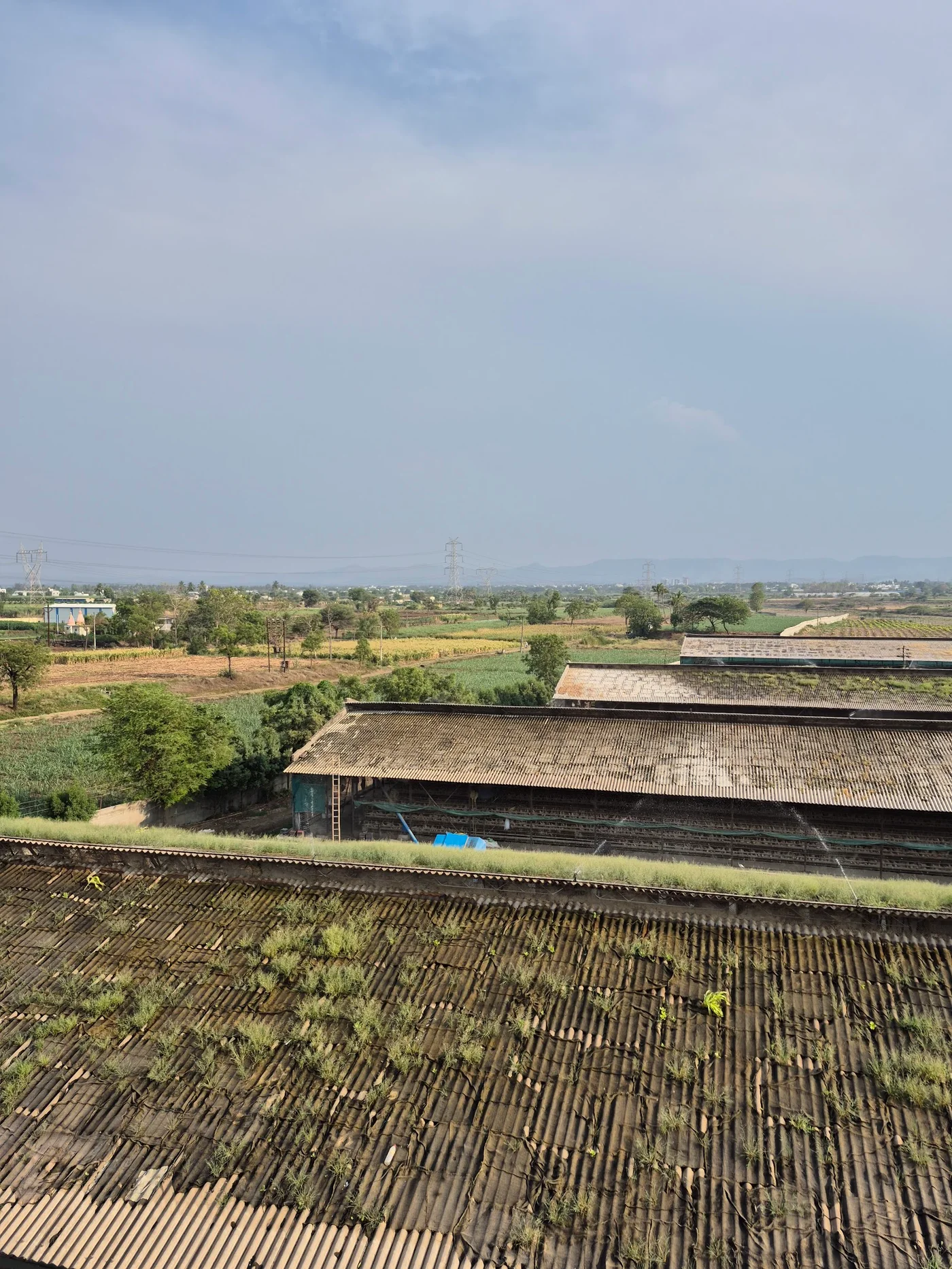 Panoramic roof view across farm buildings and open land